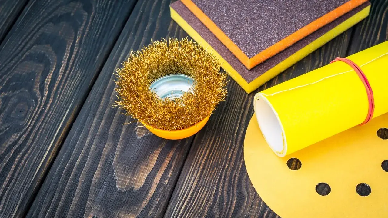 Outils de ponçage : brosse métallique, éponges abrasives et papier de verre pour préparer une surface en polyester avant l'application d'époxy.