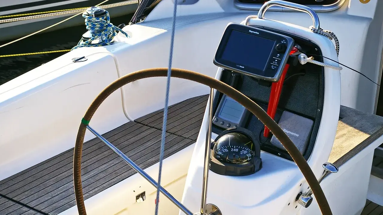 Cockpit de voilier avec barre, compas et écran Raymarine. Idéal pour un gps marine gratuit pour Android.
