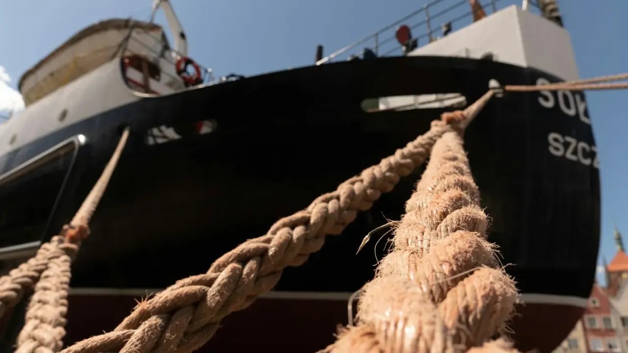 Gros cordage tressé, essentiel au point d'amarrage d'un navire noir et blanc sous un ciel bleu.