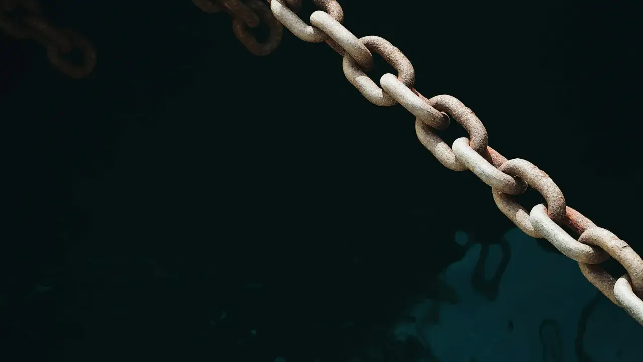 Chaîne rouillée d'une ancre de bateau, plongeant dans l'eau sombre et agitée.