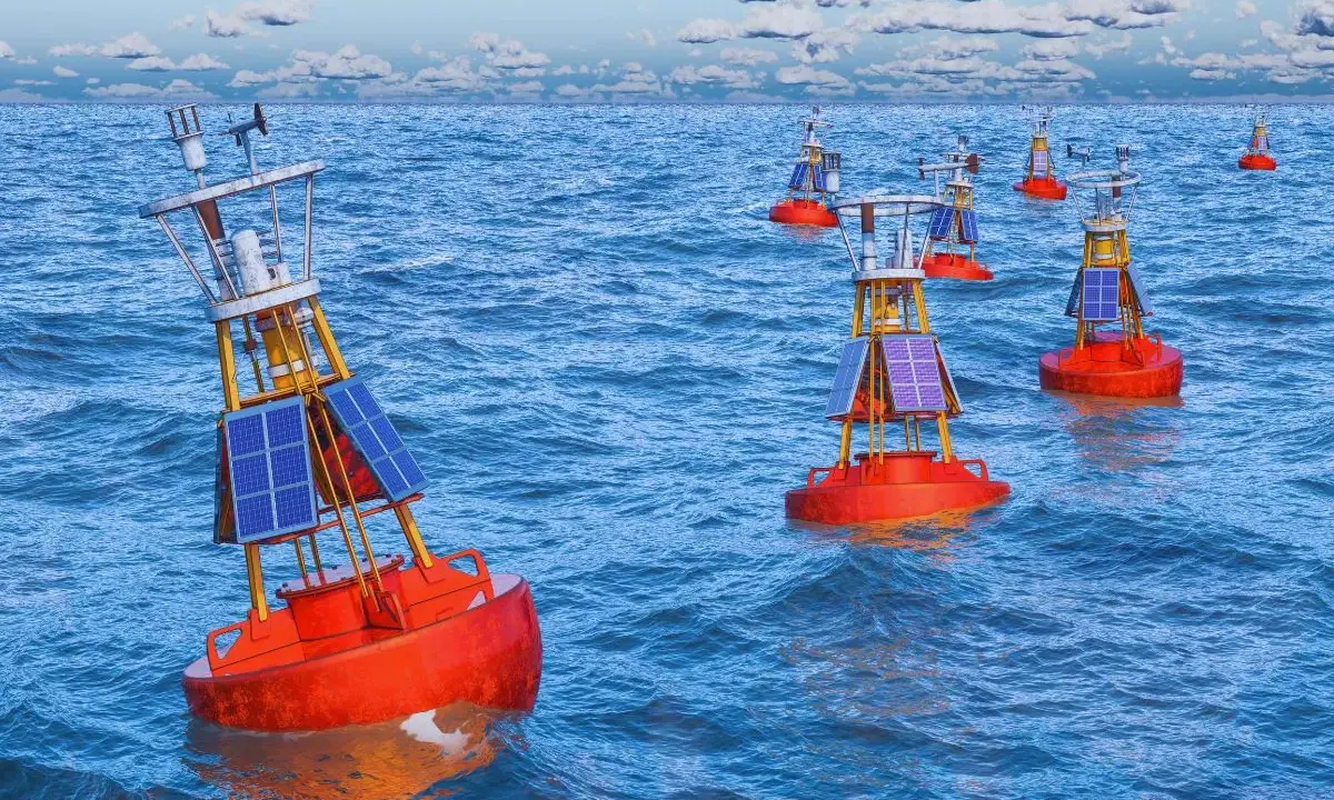 Plusieurs bouées de navigation solaires orange flottent sur une mer bleue agitée. Ces balises bateau guident les navires.