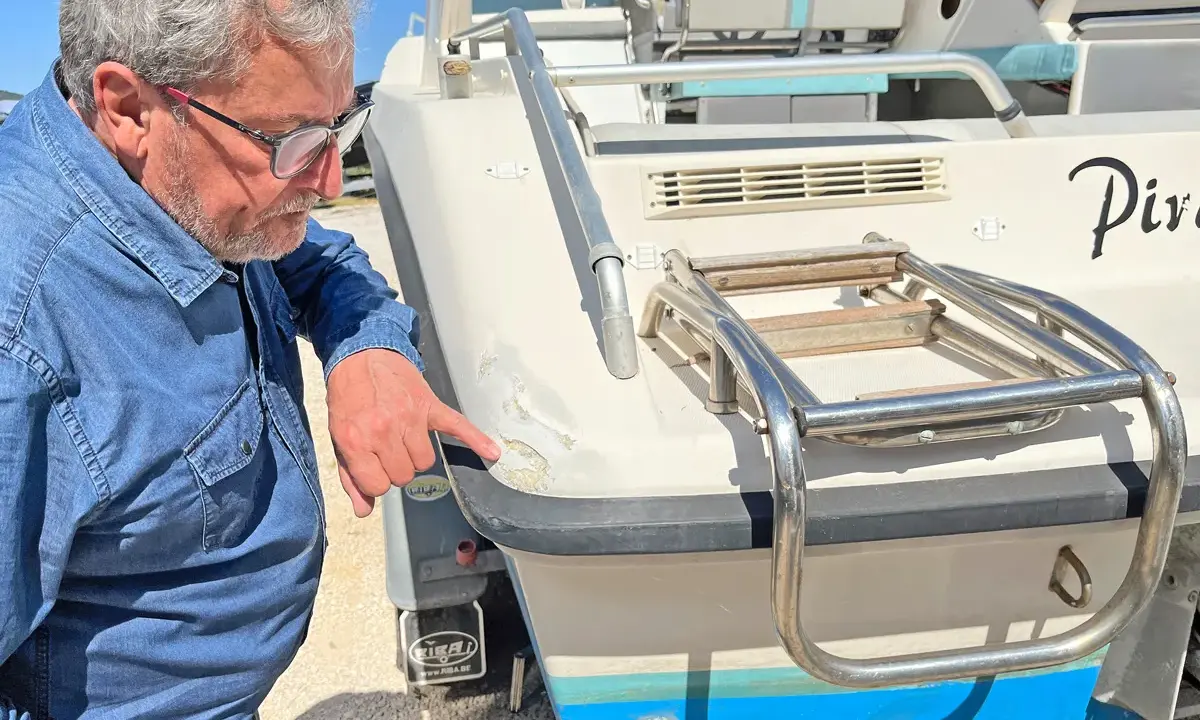 Un homme examine les dégâts sur le gelcoat d'un bateau. C'est quoi le gelcoat ? C'est la couche protectrice extérieure.