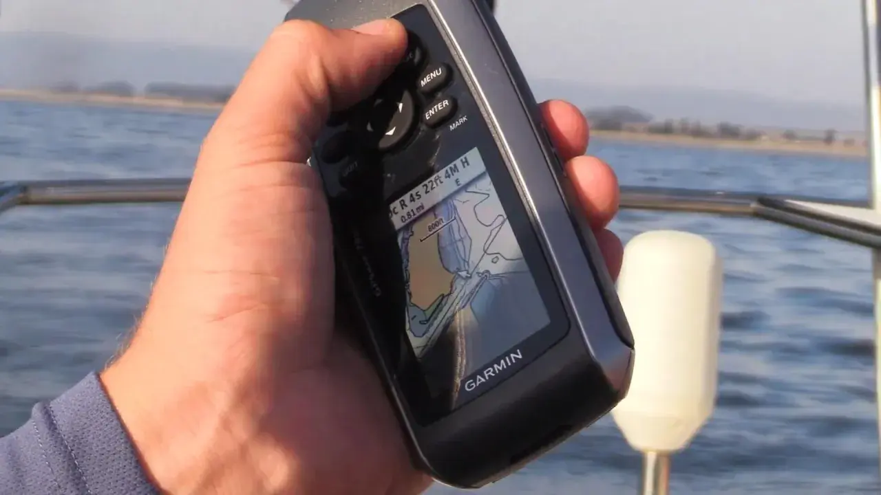Main tenant une carte GPS Garmin sur un bateau, naviguant sur l'eau.