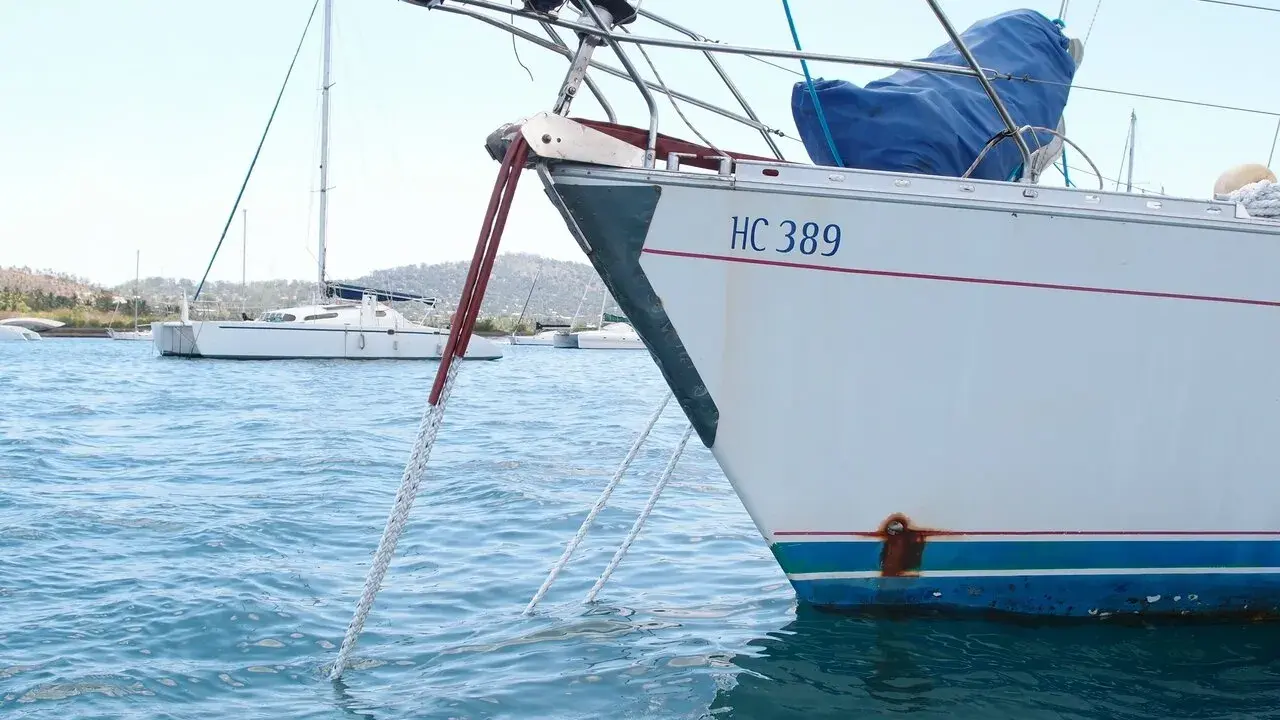 Poids corps mort pour bateau : une ancre est immergée dans l'eau bleue, attachée à un voilier blanc immatriculé HC 389.