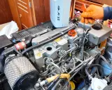 Main d'une personne en gant orange vérifiant le niveau d'huile d'un moteur 4 temps ne démarre pas. Bidon d'huile 25W40 à proximité.