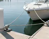 Bateau blanc amarré à un quai avec des cordages et des taquets.