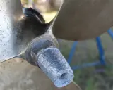 Gros plan sur l'hélice d'un bateau, montrant l'usure de l'anode et les détails gravés.