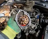 Main d'un mécanicien tenant la turbine d'une pompe à eau pour changer la turbine du moteur hors bord Suzuki.