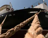 Gros cordage tressé, essentiel au point d'amarrage d'un navire noir et blanc sous un ciel bleu.