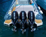 Trois puissants moteurs hors-bord noirs et rouges, prêts à propulser une chaise de luxe sur l'eau.