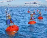 Plusieurs bouées de navigation solaires orange flottent sur une mer bleue agitée. Ces balises bateau guident les navires.