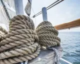 Gros cordages enroulés sur un voilier, prêts pour le moteur fonctionnement. La mer bleue et le ciel clair en arrière-plan.