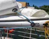 Poulie pour prise de ris automatique sur un mât de bateau, avec des cordages bleus et roses.