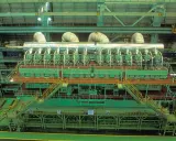 Vue aérienne d'un moteur de bateau massif, le plus gros moteur de bateau jamais construit, avec des ouvriers inspectant son imposante structure verte et argentée.