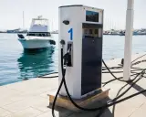 Borne de recharge pour bateaux, avec un tuyau prêt à l'emploi. L'eau bleue et les voiliers en arrière-plan rappellent que l'essence trop vieille n'est pas une option ici.
