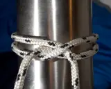 Un nœud pare battage, simple et efficace, sécurise une corde blanche et noire autour d'un mât métallique.