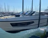 Un bateau blanc est soulevé par une grue, sa coque reflétant le soleil sur la surface mouillée du port.