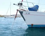 Poids corps mort pour bateau : une ancre est immergée dans l'eau bleue, attachée à un voilier blanc immatriculé HC 389.