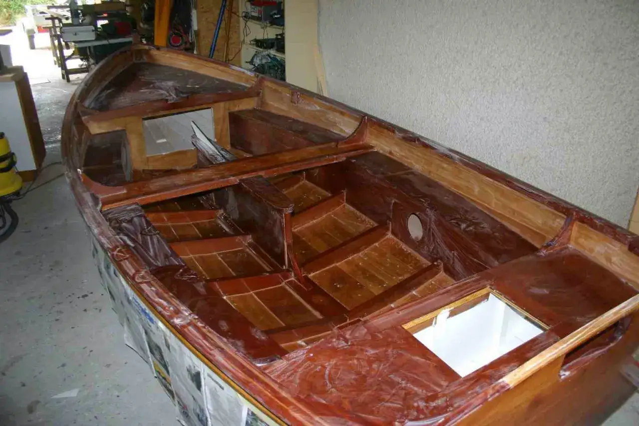 Intérieur d'un bateau en bois verni, en cours de restauration. La peinture du bateau bois révèle la beauté des lattes et des bancs.