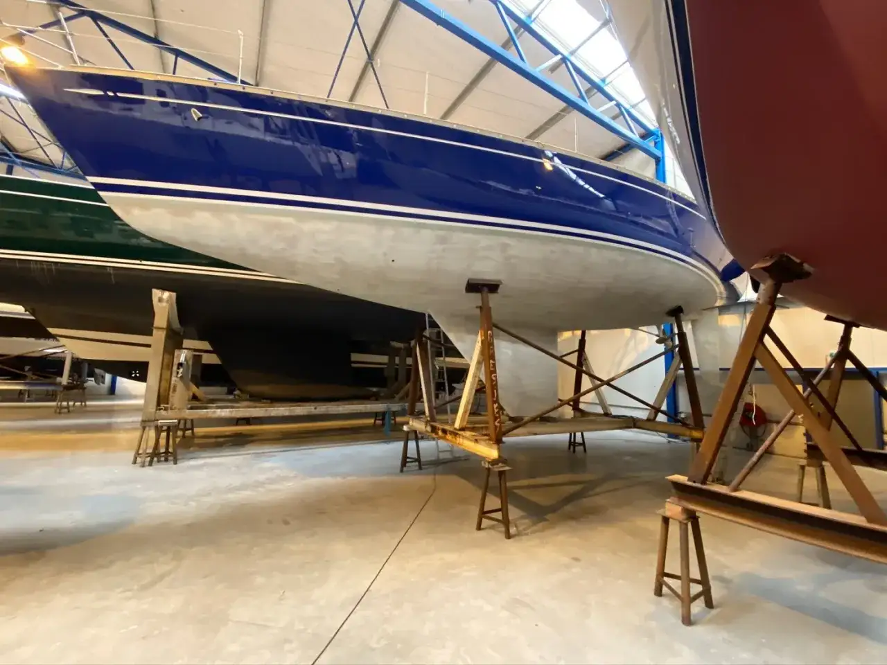 Bateaux bleus et rouges sur des berceaux dans un atelier, prêts pour la finition avec de la résine de stratification.