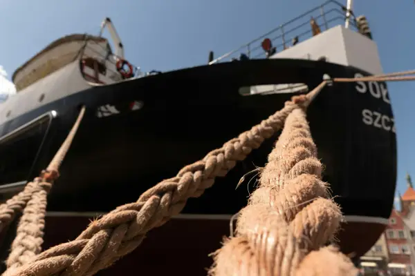 Gros cordage tressé, essentiel au point d'amarrage d'un navire noir et blanc sous un ciel bleu.