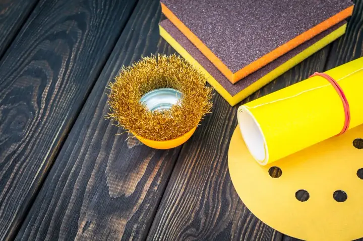 Outils de ponçage : brosse métallique, éponges abrasives et papier de verre pour préparer une surface en polyester avant l'application d'époxy.