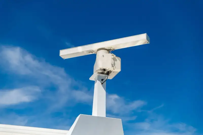 Antenne blanche sur un mât, sous un ciel bleu. Elle ressemble à un radar, mais pourrait aussi servir pour la communication satellite.